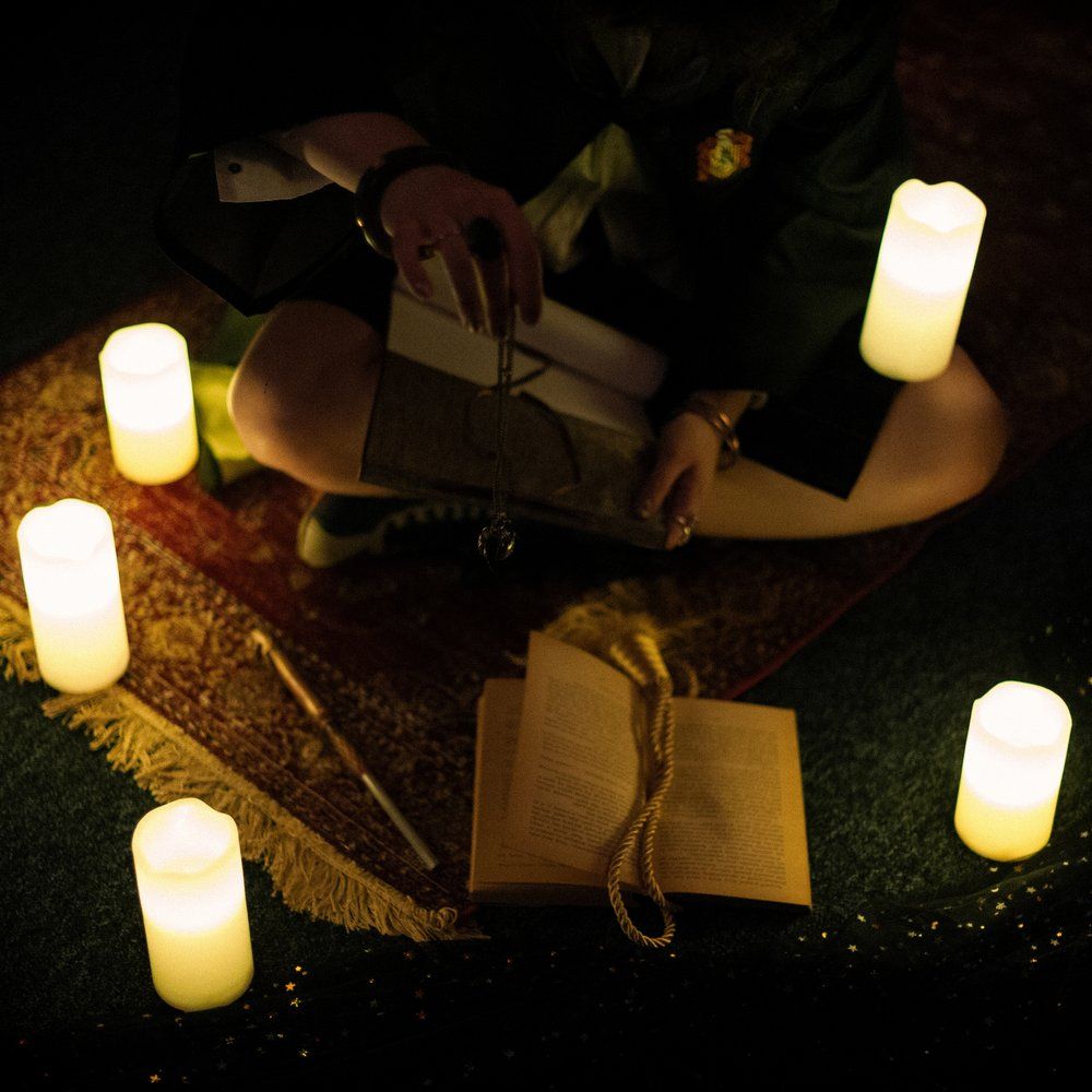 A student of the magic academy among candles, with a scroll and spellbook – Return of the Sorcerer, Keyword Warsaw