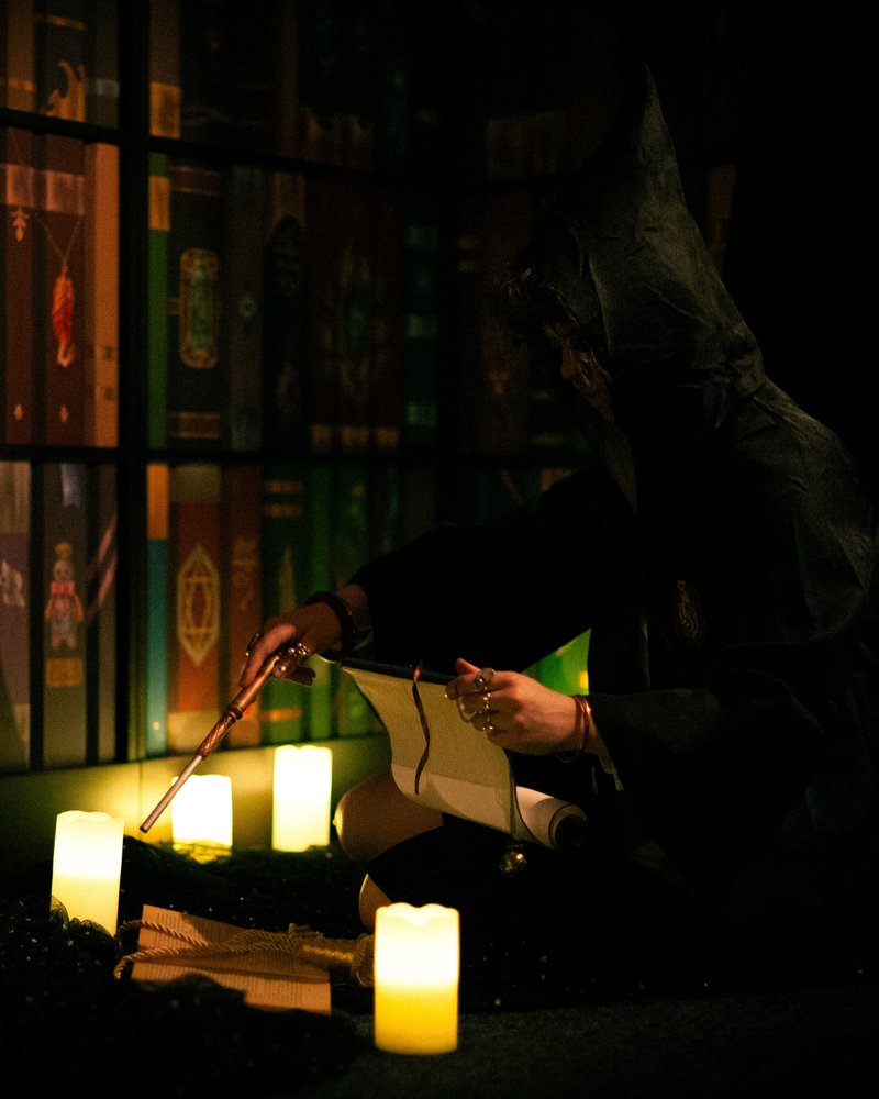 A hooded figure with a wand and a scroll among candles – the Return of the Sorcerer room at Keyword escape room, Warsaw